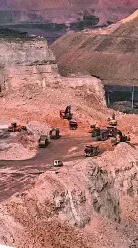 Open-pit mine with haul trucks and excavators working a bench face